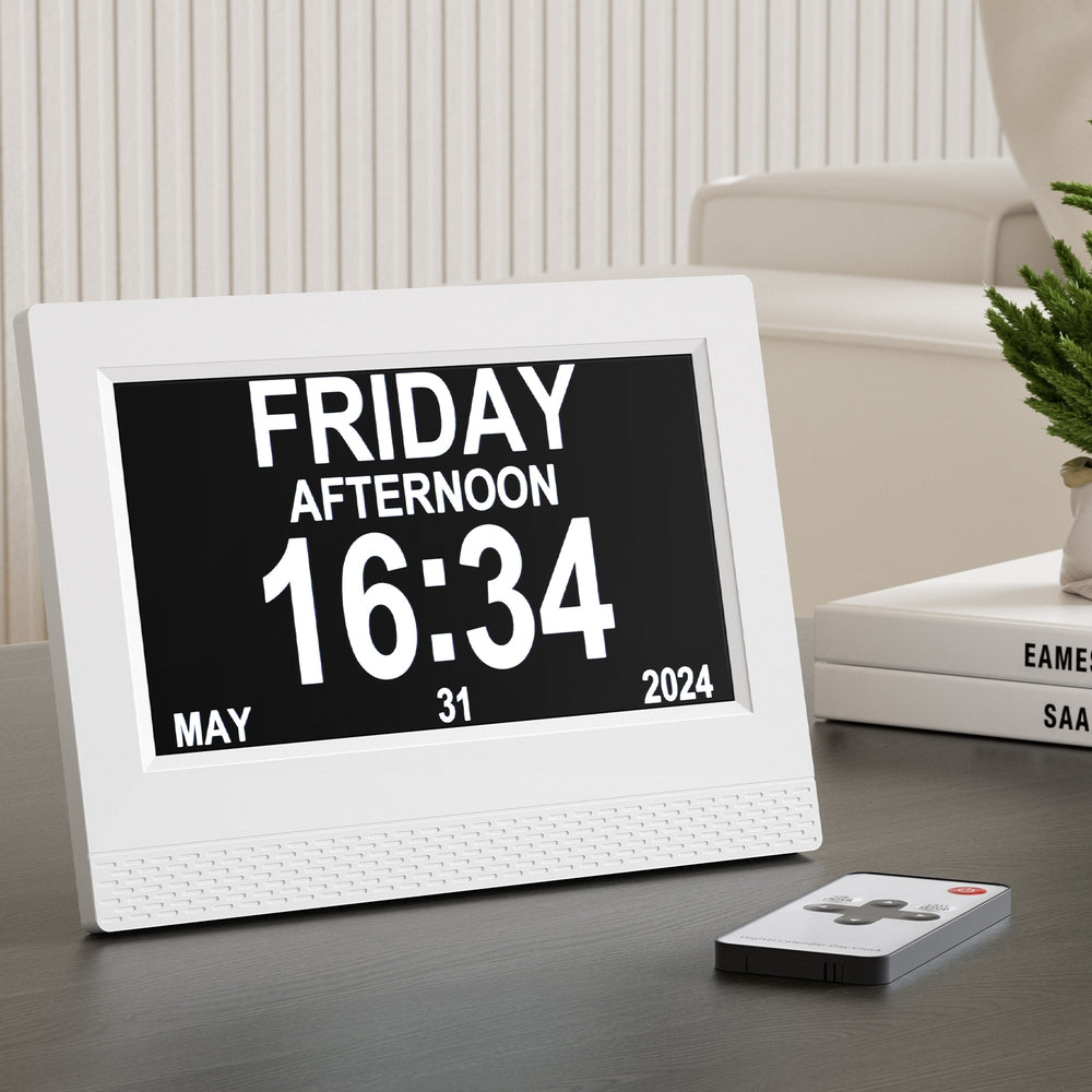 Digital clock displaying 'FRIDAY AFTERNOON 16:34' on a table with a remote control.