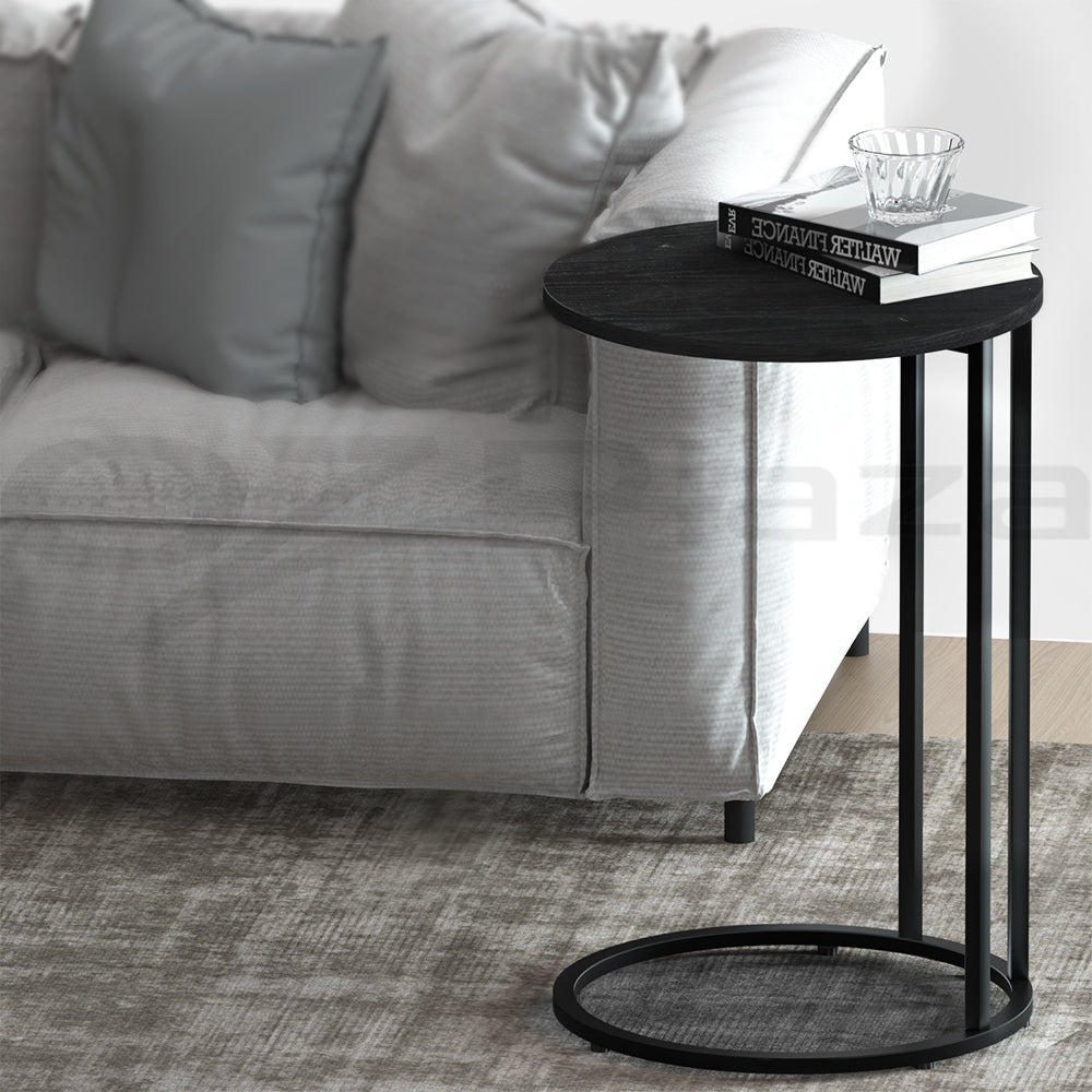 Black side table in front of a gray sofa with a book on top