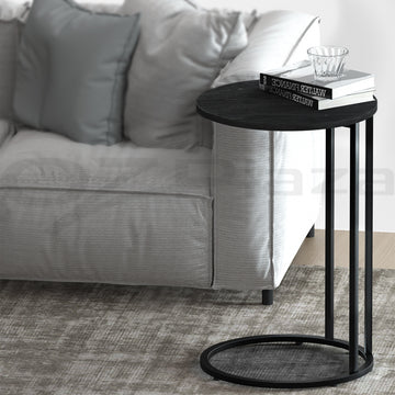 Black side table in front of a gray sofa with a book on top