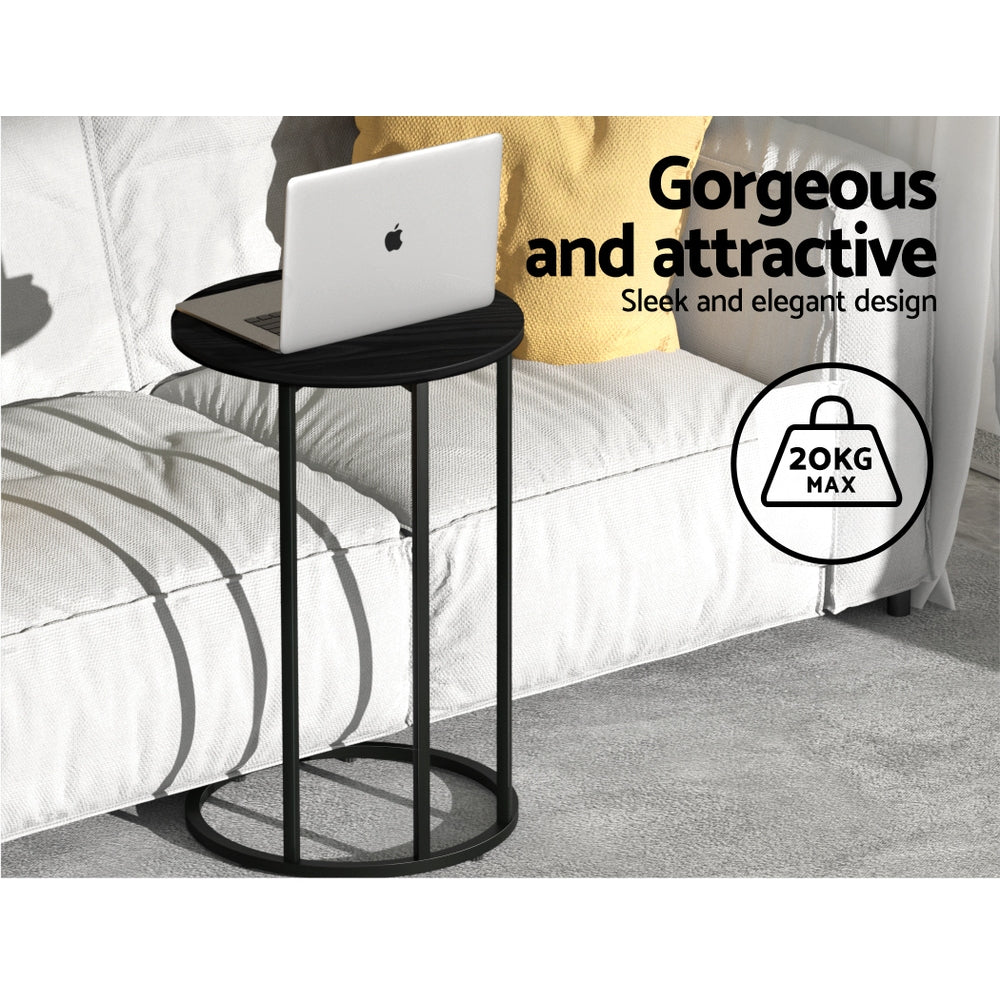 Black side table with a laptop on it, placed against a white sofa.