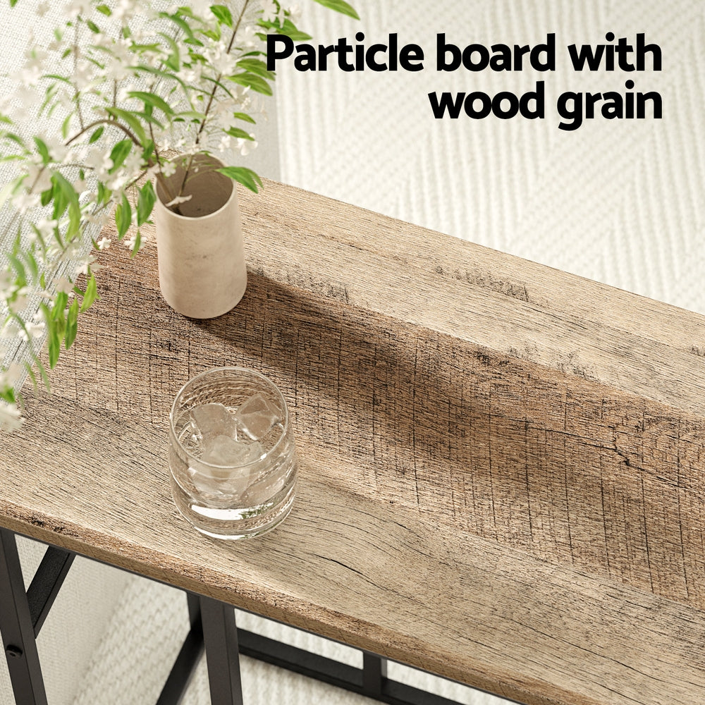 Particle board with wood grain texture on a surface with a glass and plant.
