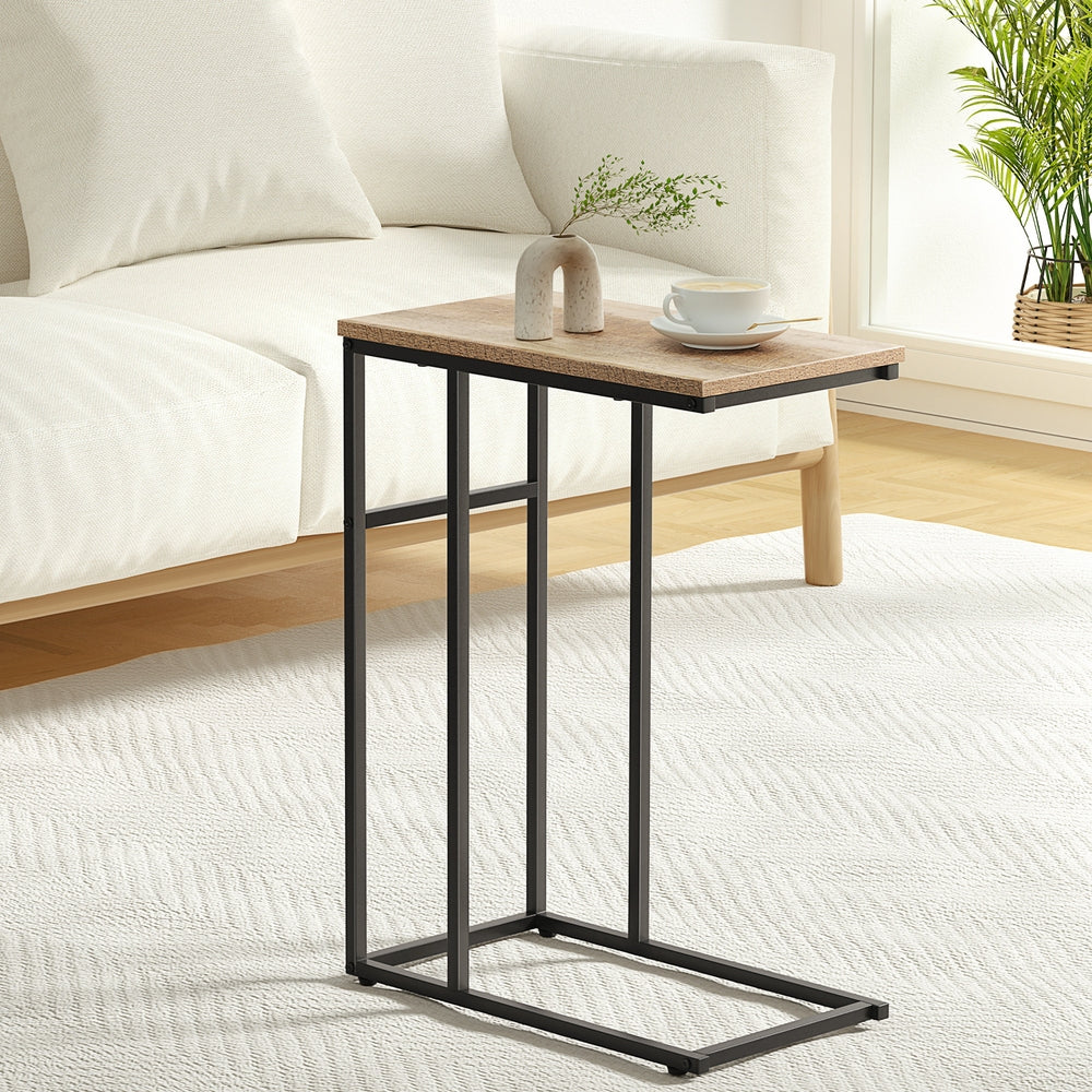 Small wooden side table with black metal legs in a bedroom setting.