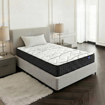 Mattress on a bed in a bedroom setting with lamps and curtains.