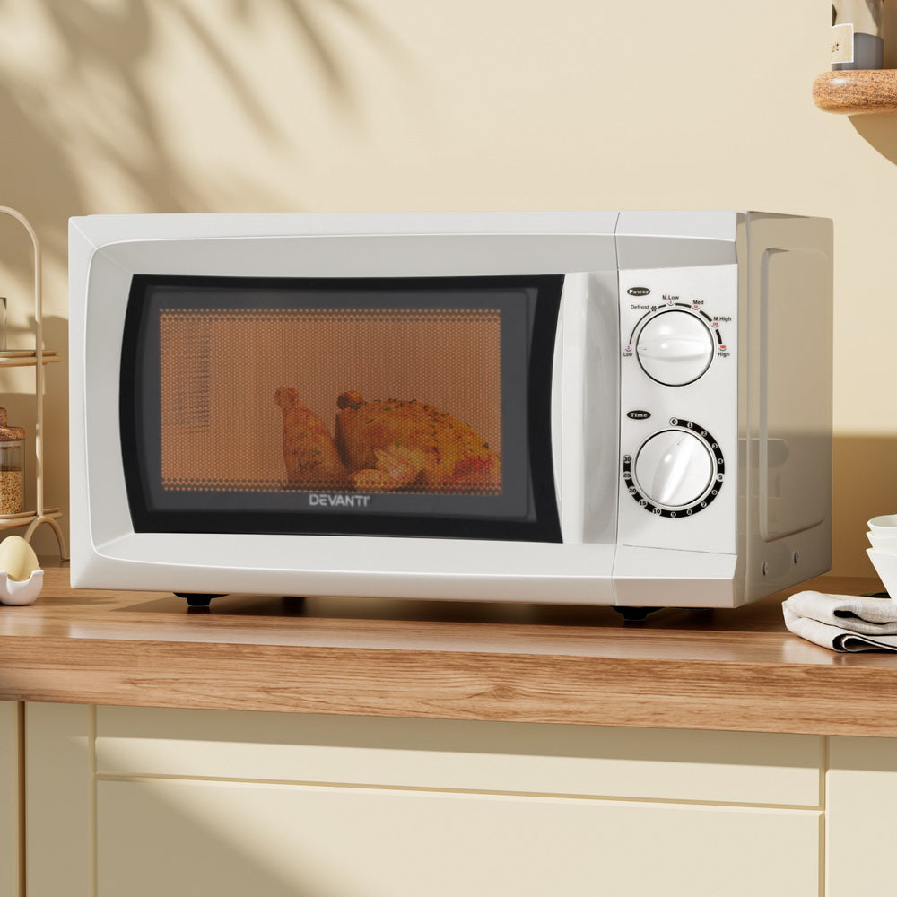 White microwave oven on a wooden countertop with a kitchen setting.
