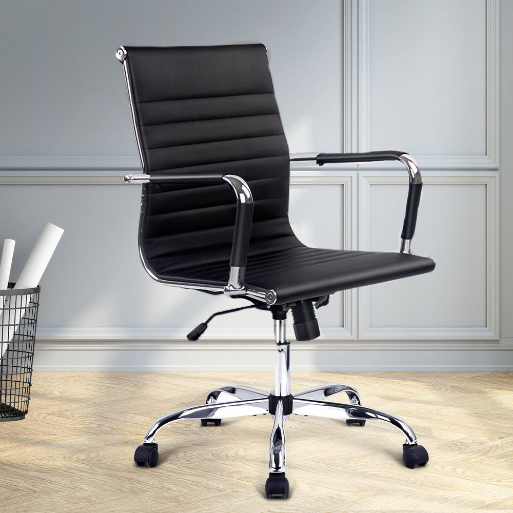 Black office chair with chrome accents in a room with light wood flooring and white walls.