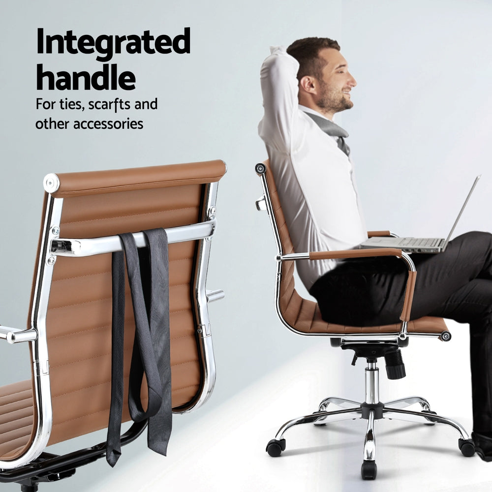 Man sitting on a brown office chair with a laptop, next to a folded suit on another chair.