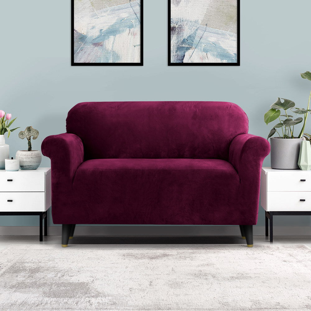 Magenta sofa in a living room with abstract art on the wall and white furniture.