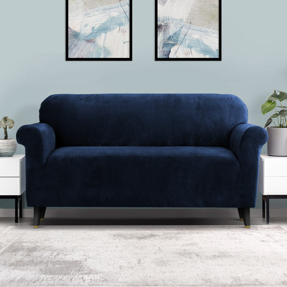 Navy blue sofa in a room with abstract art on the wall and white furniture.