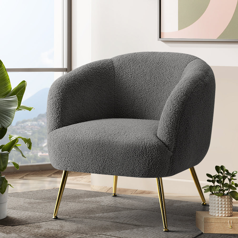 Gray textured armchair with gold legs in a room with plants and a window.