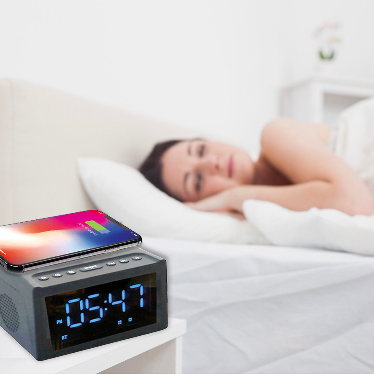 Woman lying in bed with a digital clock and smartphone displaying a colorful screen.