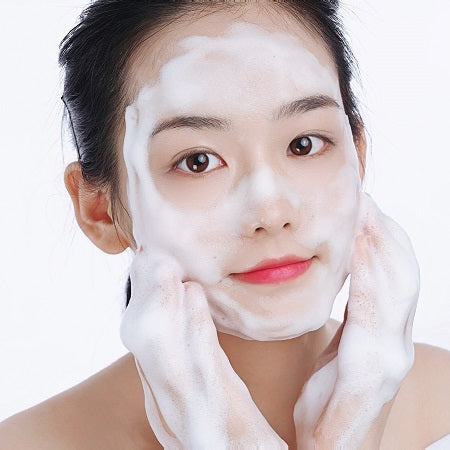 Woman applying white cream to her face against a white background
