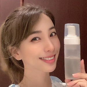 Woman holding a skincare product bottle with a blurred background