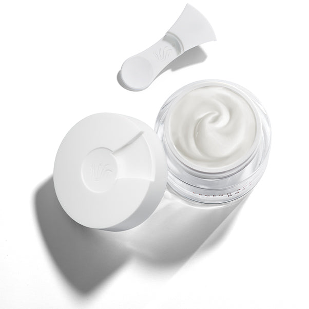 Open jar of white cream with a applicator on a white background