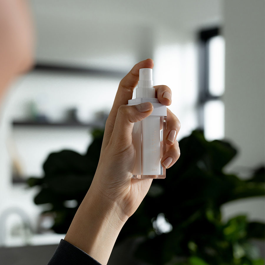 Hand holding a white spray bottle with a blurred indoor background