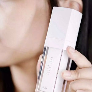 Person holding a skincare product close to their face