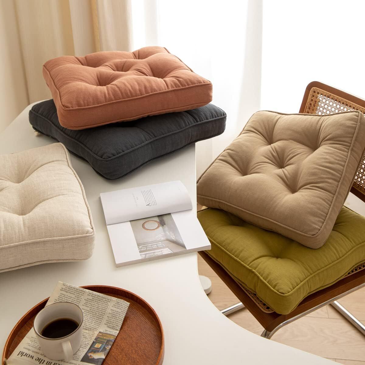 Collection of various cushioned floor pillows on a table with a magazine and coffee cup.