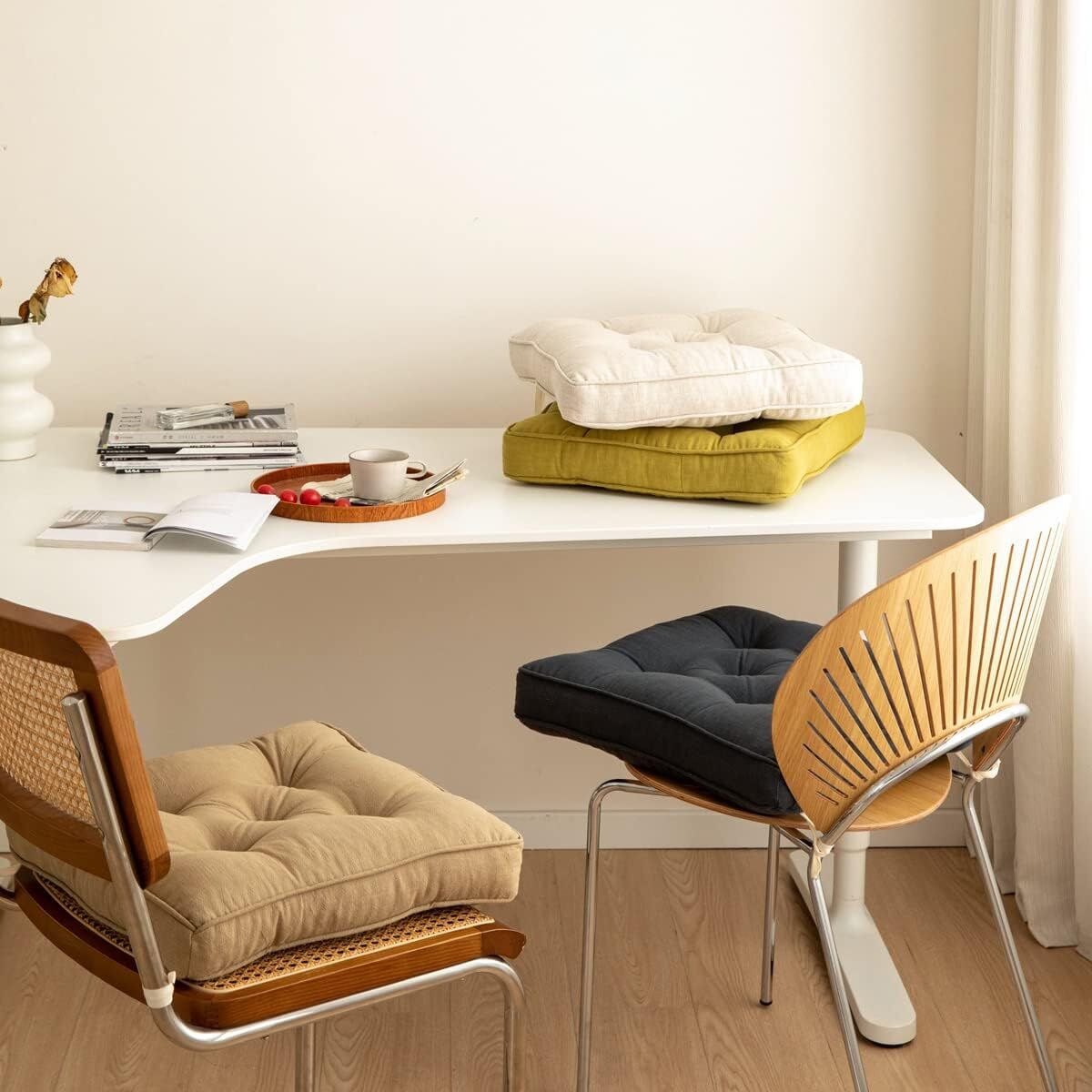 Two chairs with cushions in a room with a table and books.