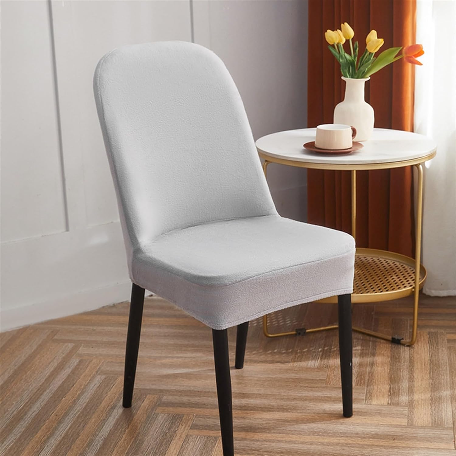 Gray chair with black legs in a room with a small table and flowers.