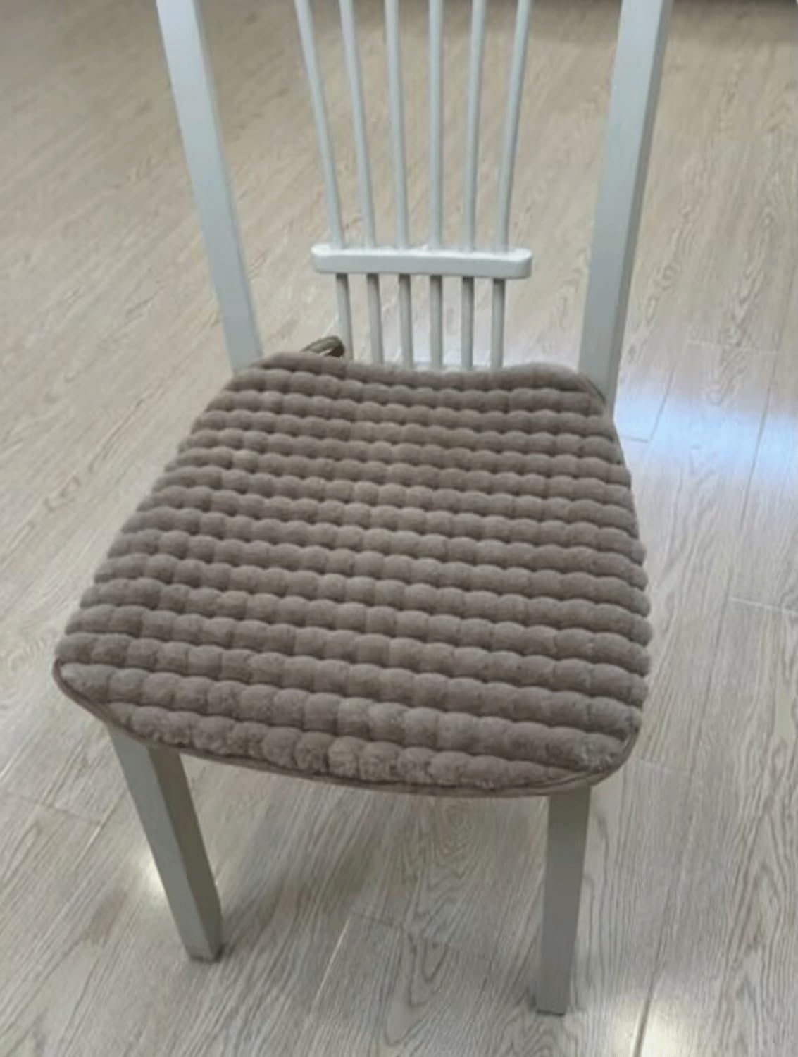 Brown textured chair pad on a wooden chair with a light wood floor background