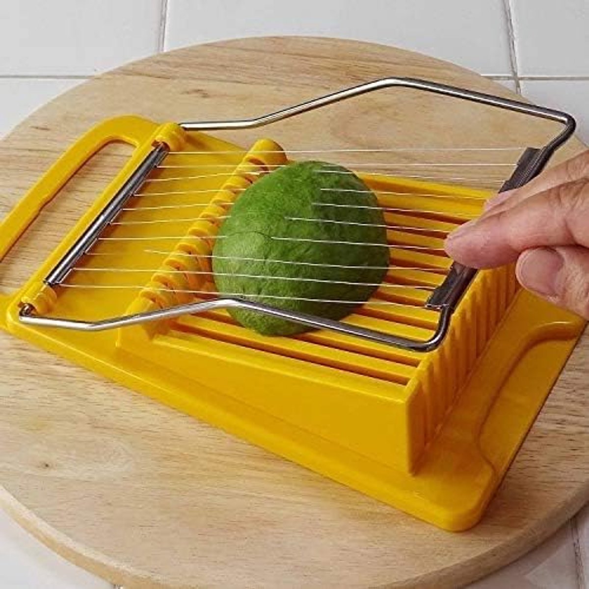 Yellow vegetable slicer with a green vegetable on a wooden cutting board