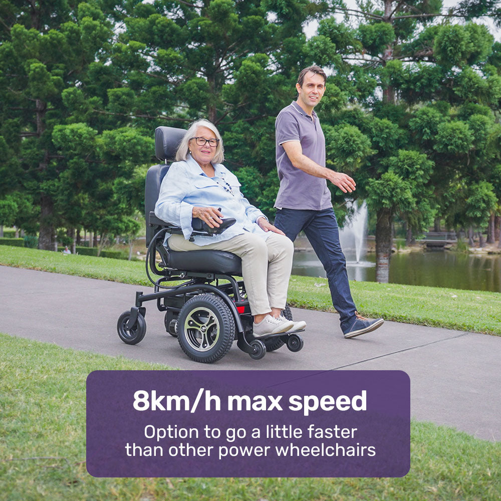 Woman in a power wheelchair being pushed by a man in a park with text about maximum speed.