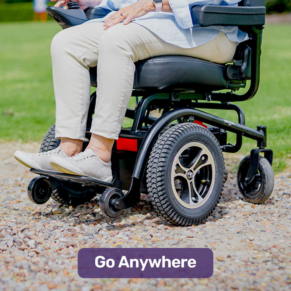 Person using a power wheelchair on a gravel path with 'Go Anywhere' text overlay.