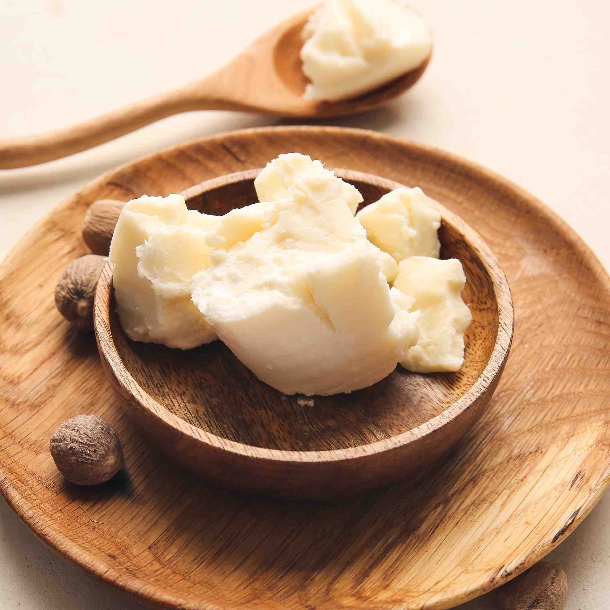 Wooden bowl filled with white cream-like substance on a wooden plate.