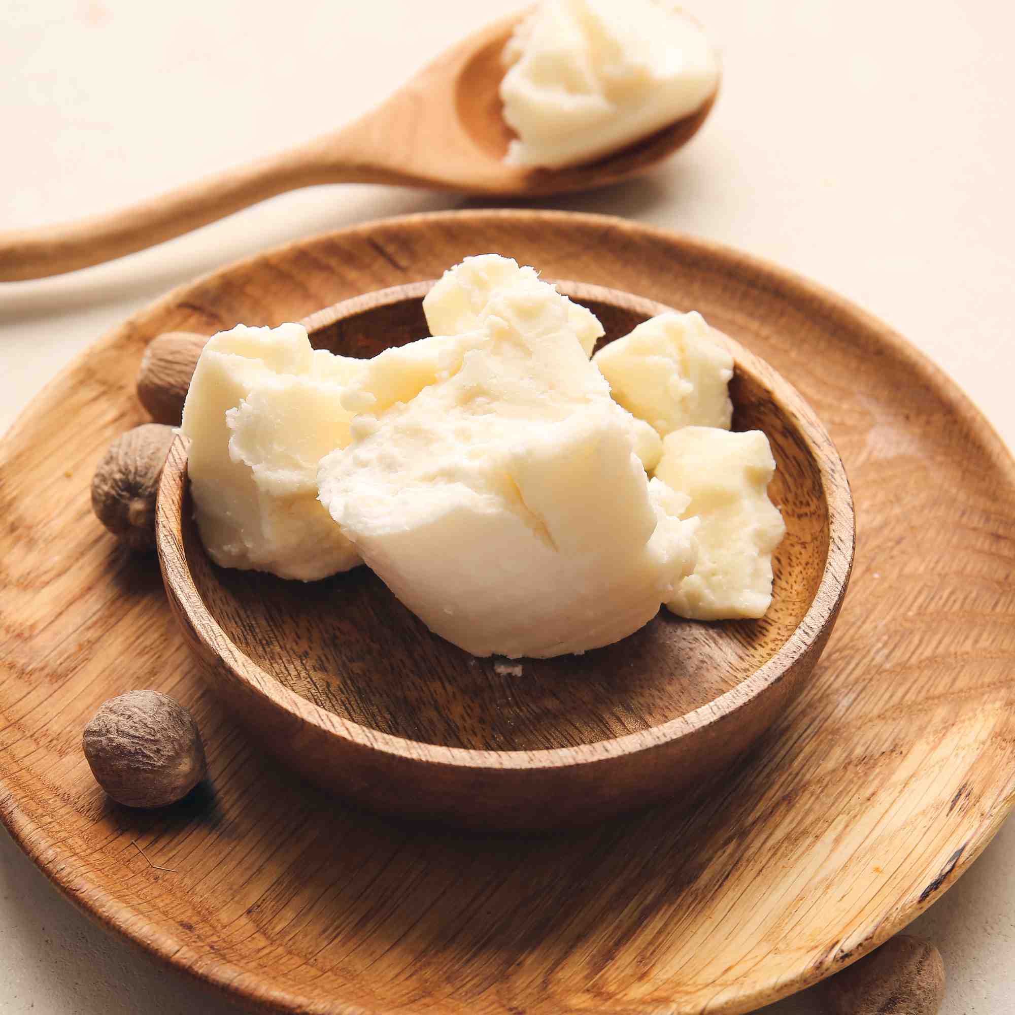 Wooden bowl filled with white cream-like substance on a wooden plate.