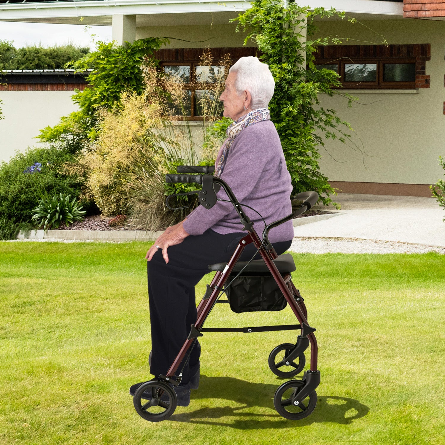 Senior woman using a walker on a grassy area in front of a house.