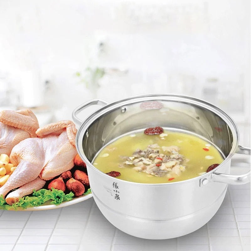 Stainless steel pot with chicken soup and raw chicken pieces on a white background