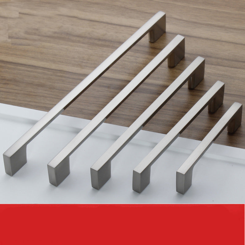 Set of metallic cabinet handles on a wooden surface with a red accent at the bottom.