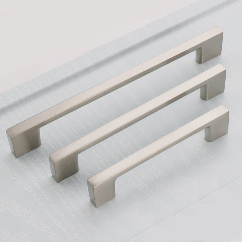 Three metallic cabinet handles on a light gray background