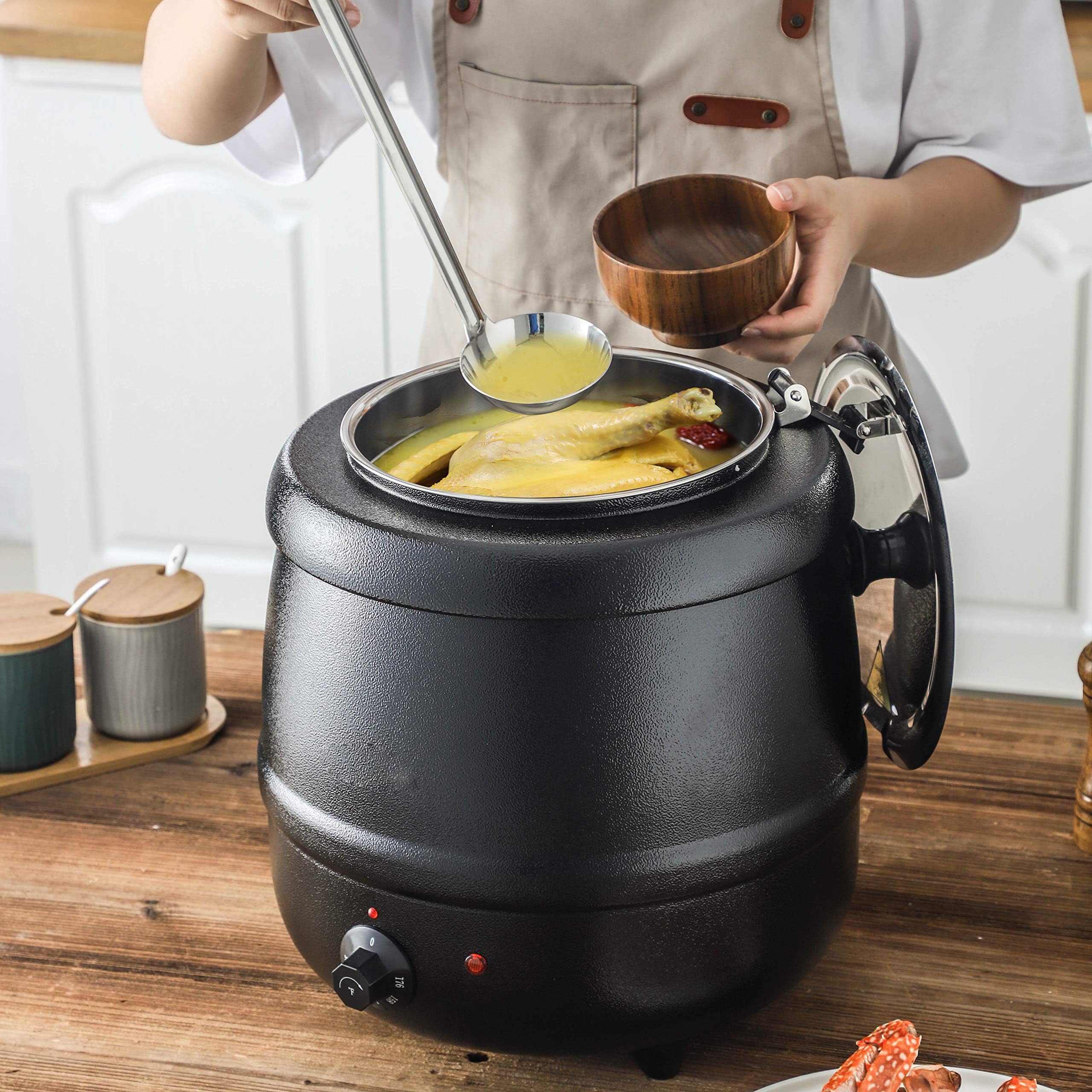 Person ladling soup from a black electric pot on a wooden table.