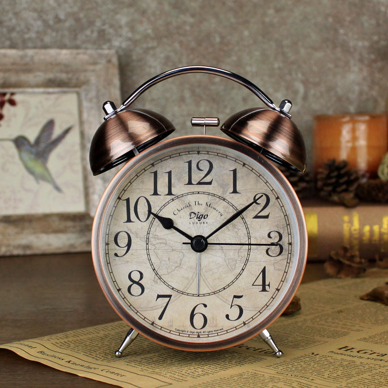 Vintage-style alarm clock with brass finish on a textured surface