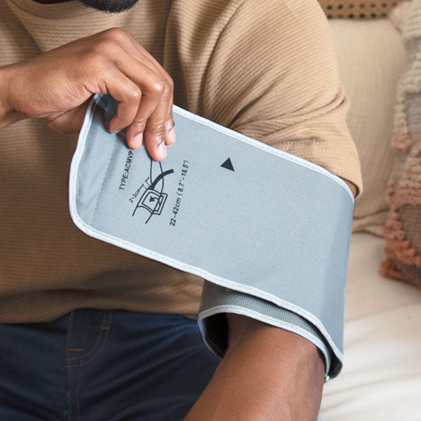 Person using a blood pressure monitor on their arm at home.