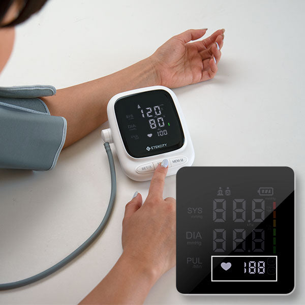 Person using a digital blood pressure monitor on a white surface