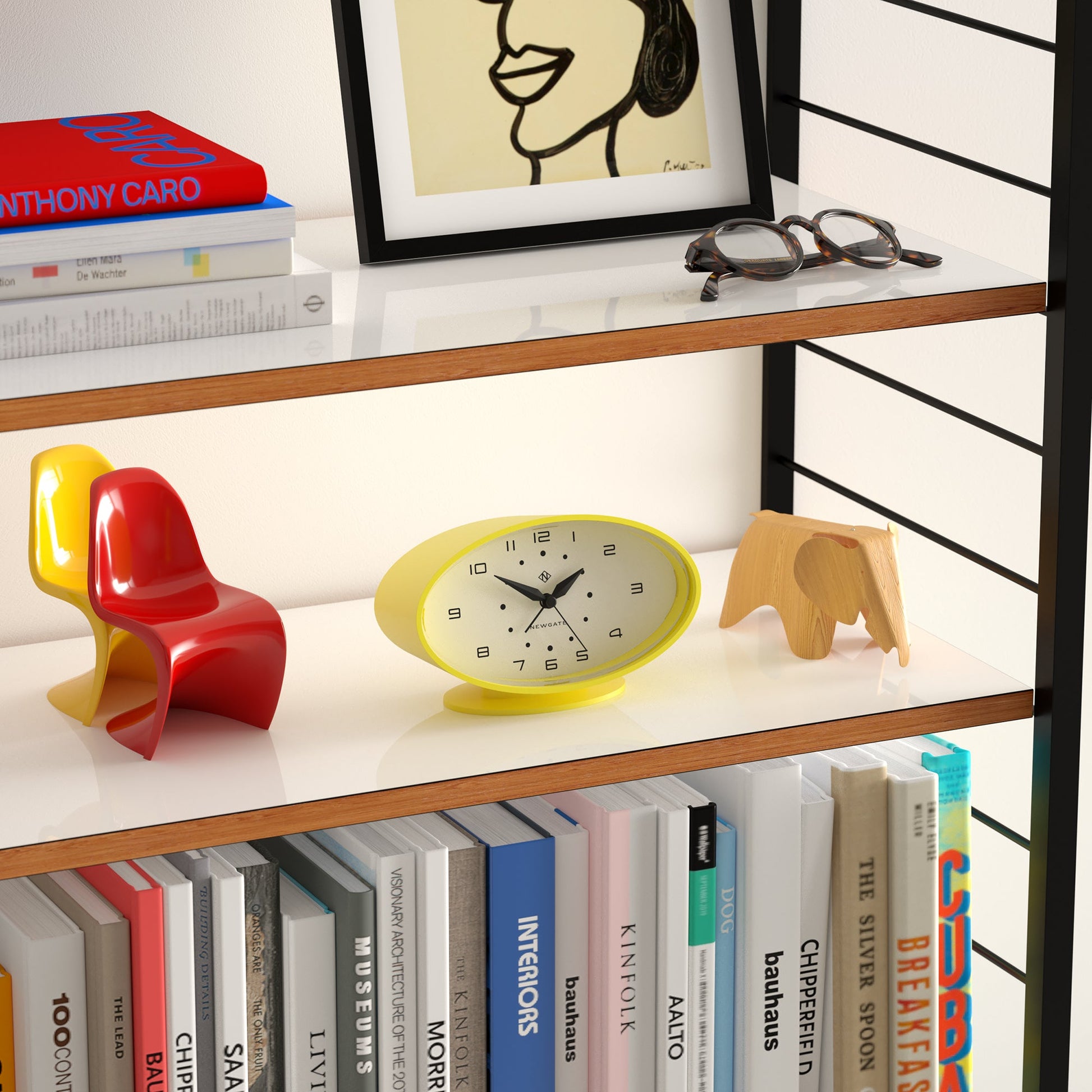 Shelf with books, colorful chair, clock, and decorative elephant on a white wall background