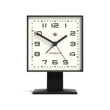 Square table clock with black frame and white face on a white background