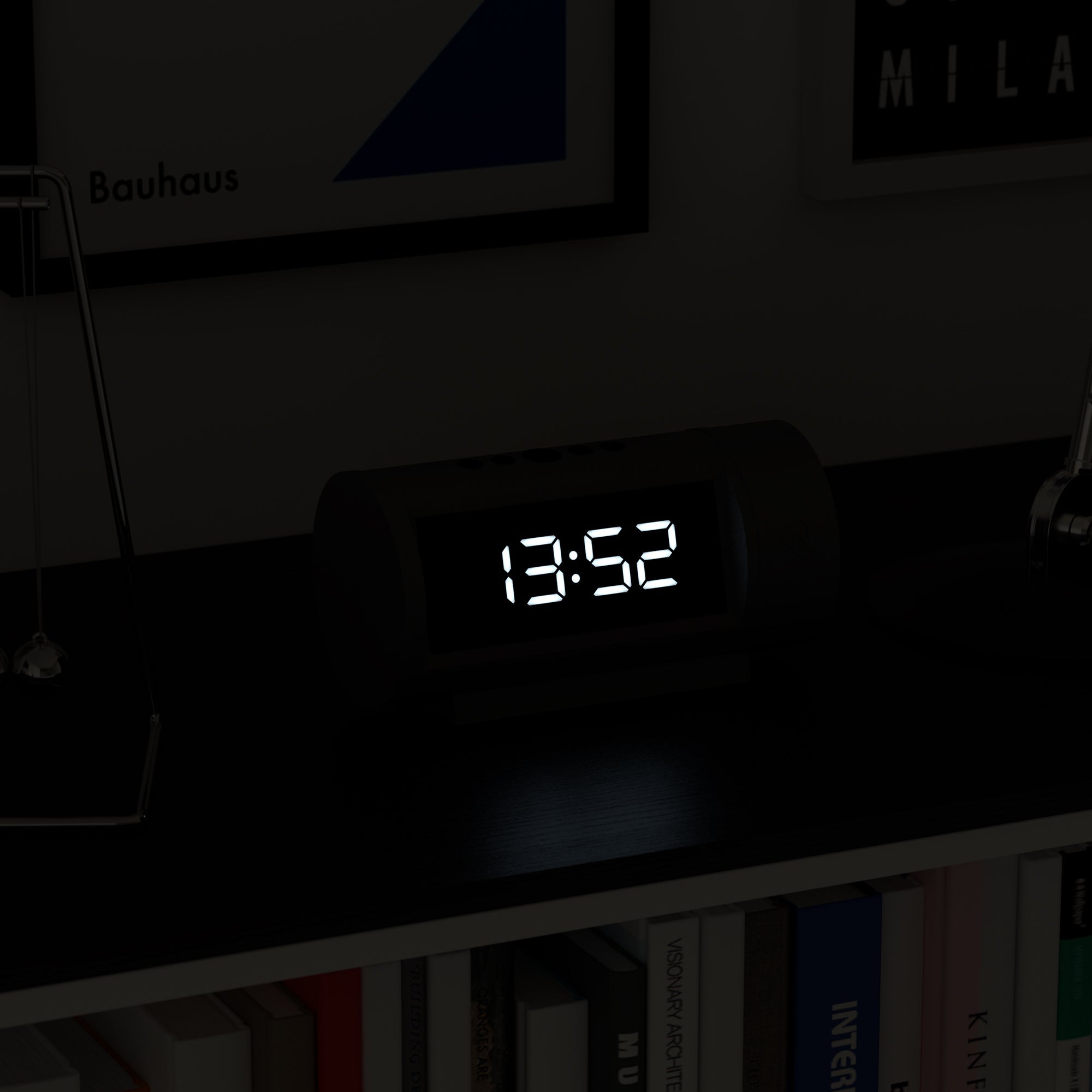 Digital clock displaying the time on a shelf with books and decorative items.
