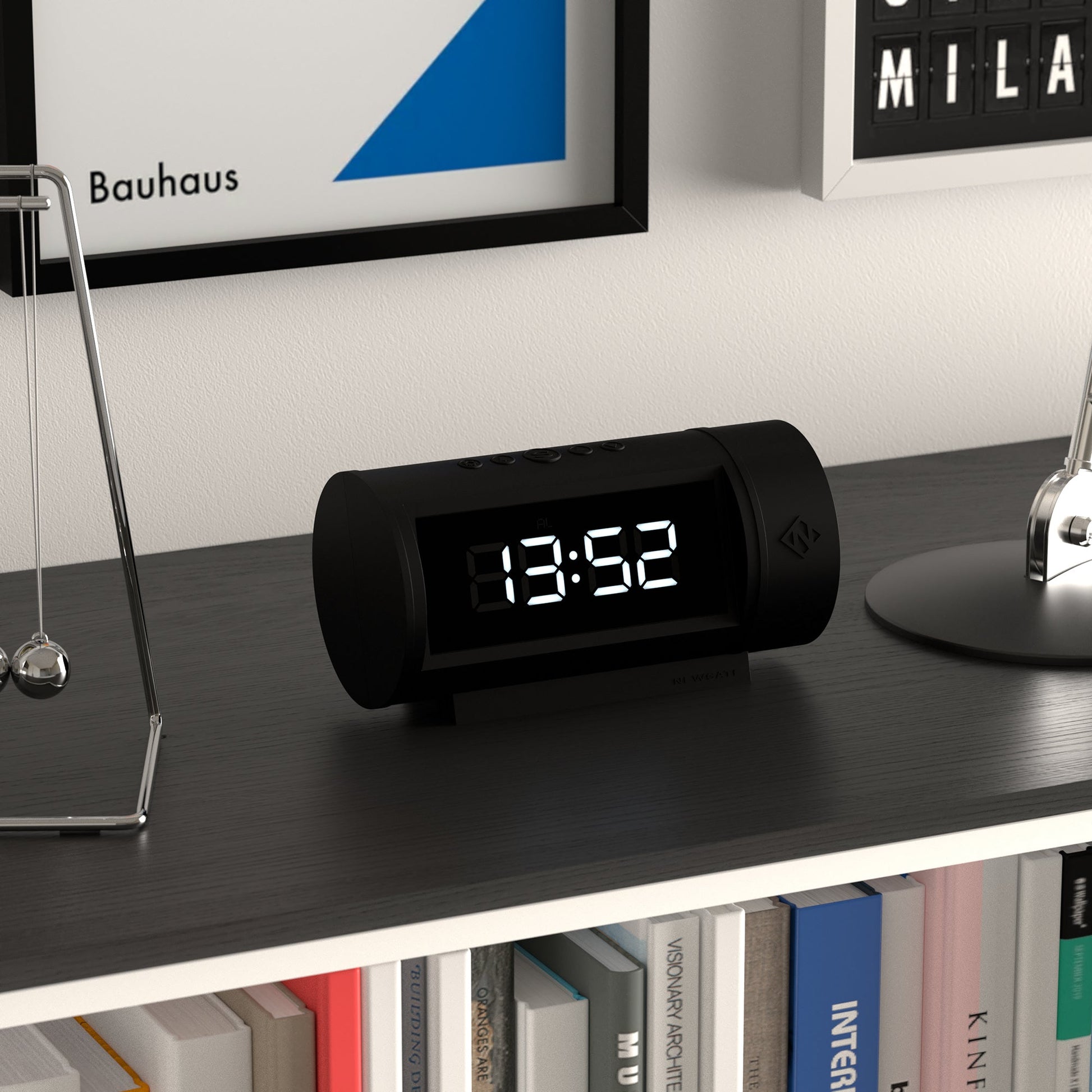 Black digital clock on a shelf with books and decorative items in the background