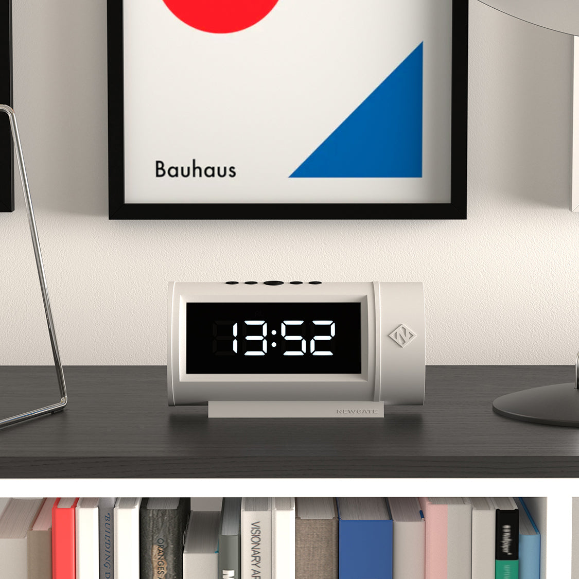 Digital clock on a desk with a Bauhaus art piece in the background