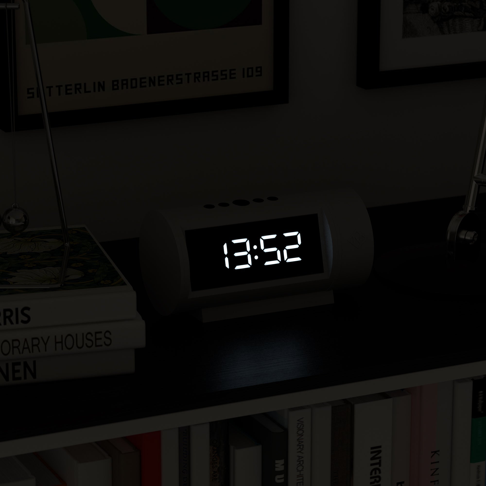 Digital clock displaying the time 13:52 on a shelf with books and decorative items.