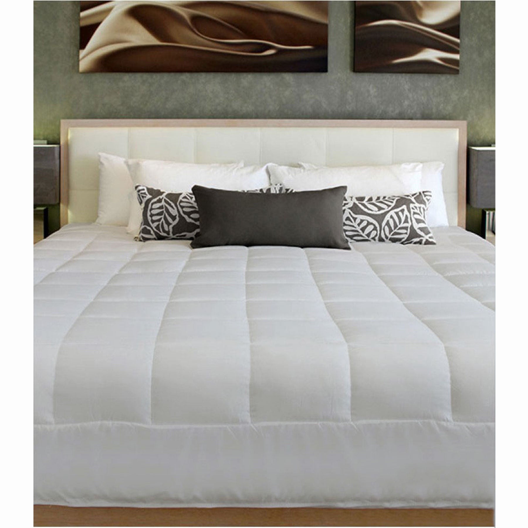 Bed with white comforter, gray pillows, and decorative pillows against a wall with abstract art.