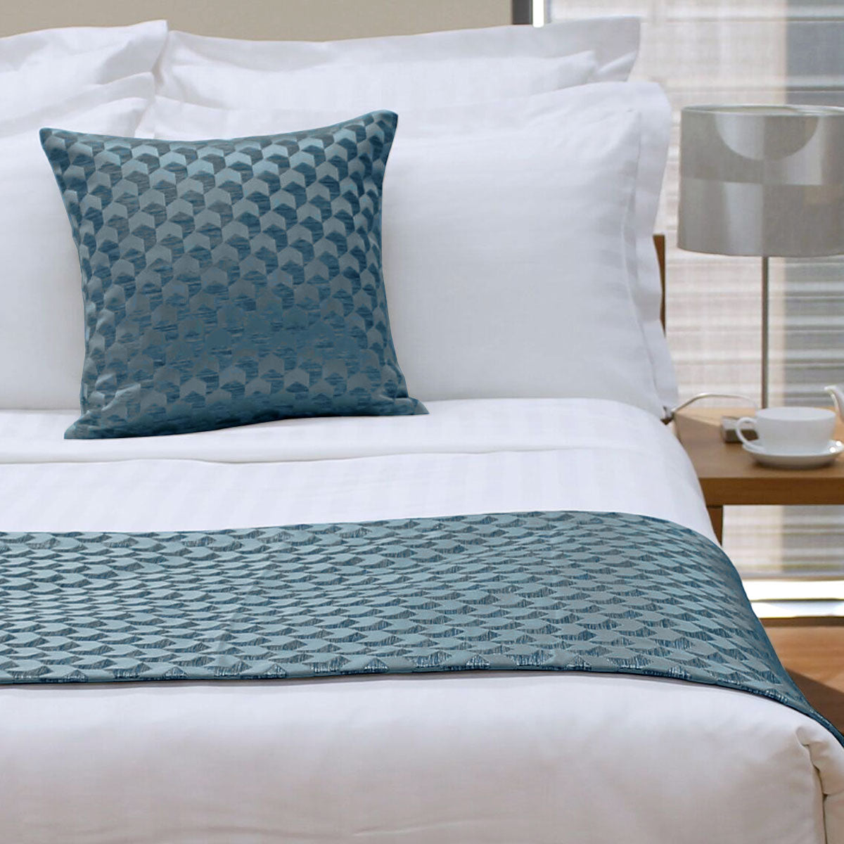 Bed with white bedding and a blue patterned throw and pillow.