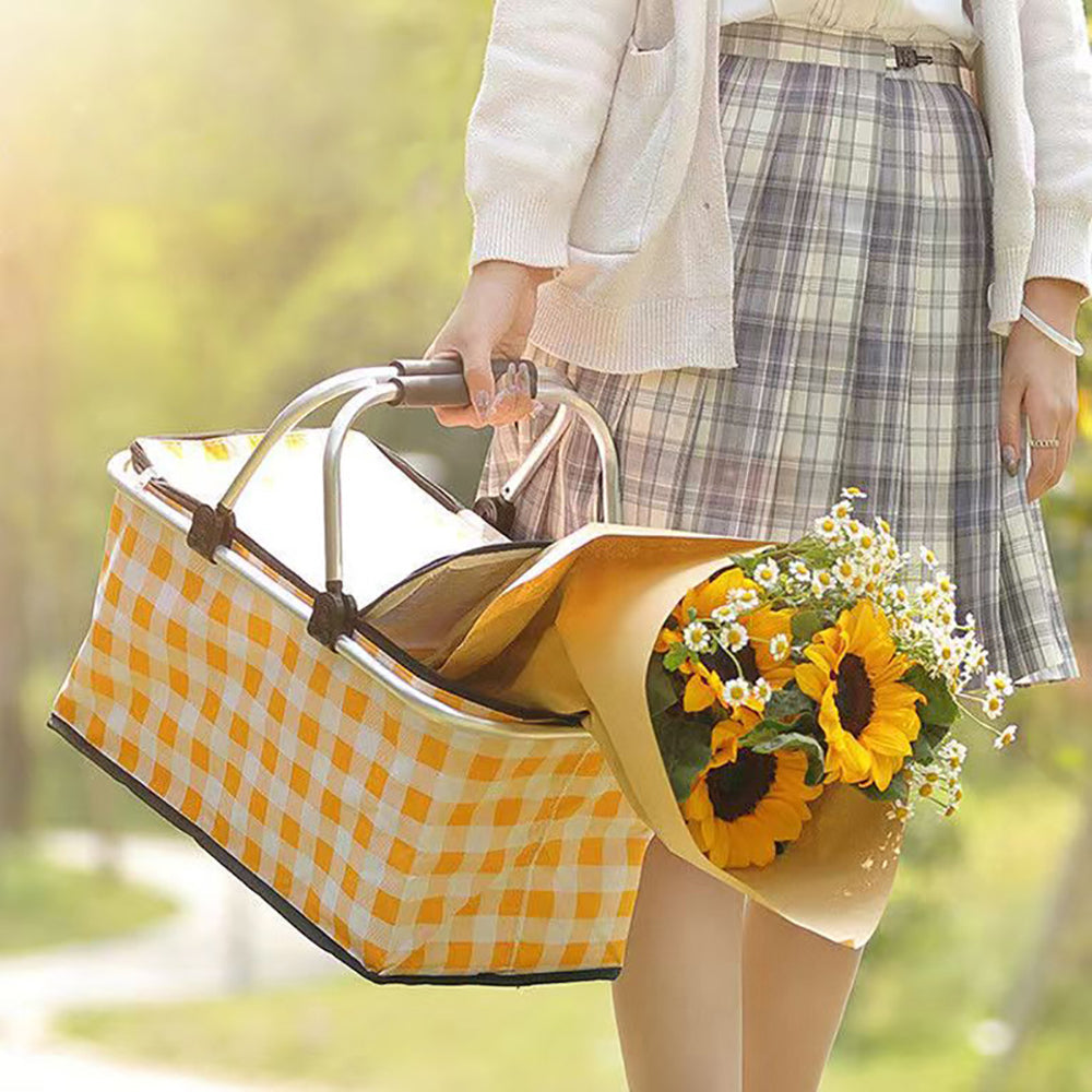 Person holding a yellow checkered bag with flowers outdoors