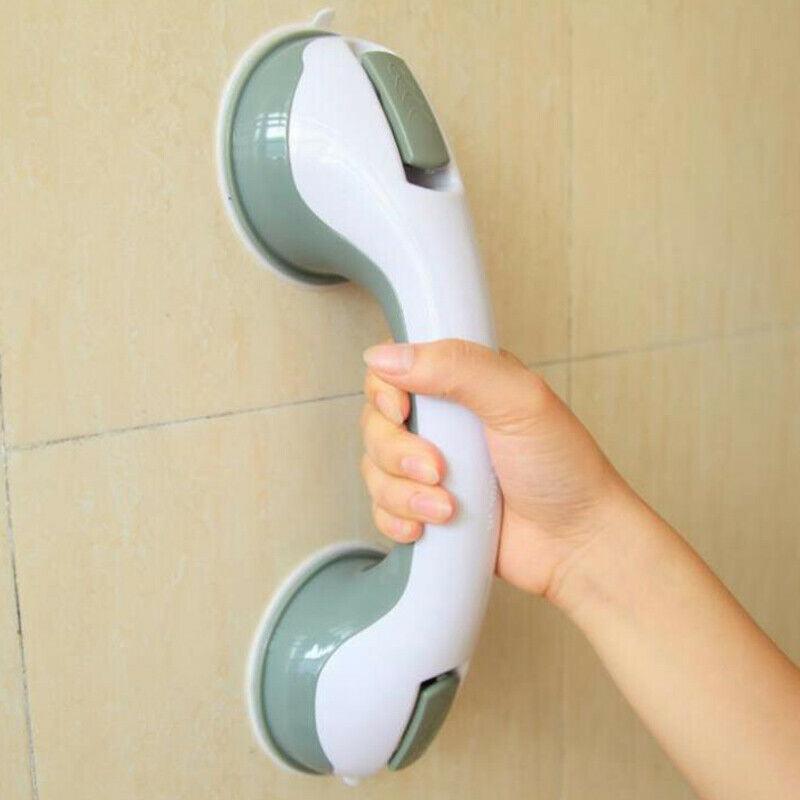 Hand holding a green and white grab bar against a tiled wall.