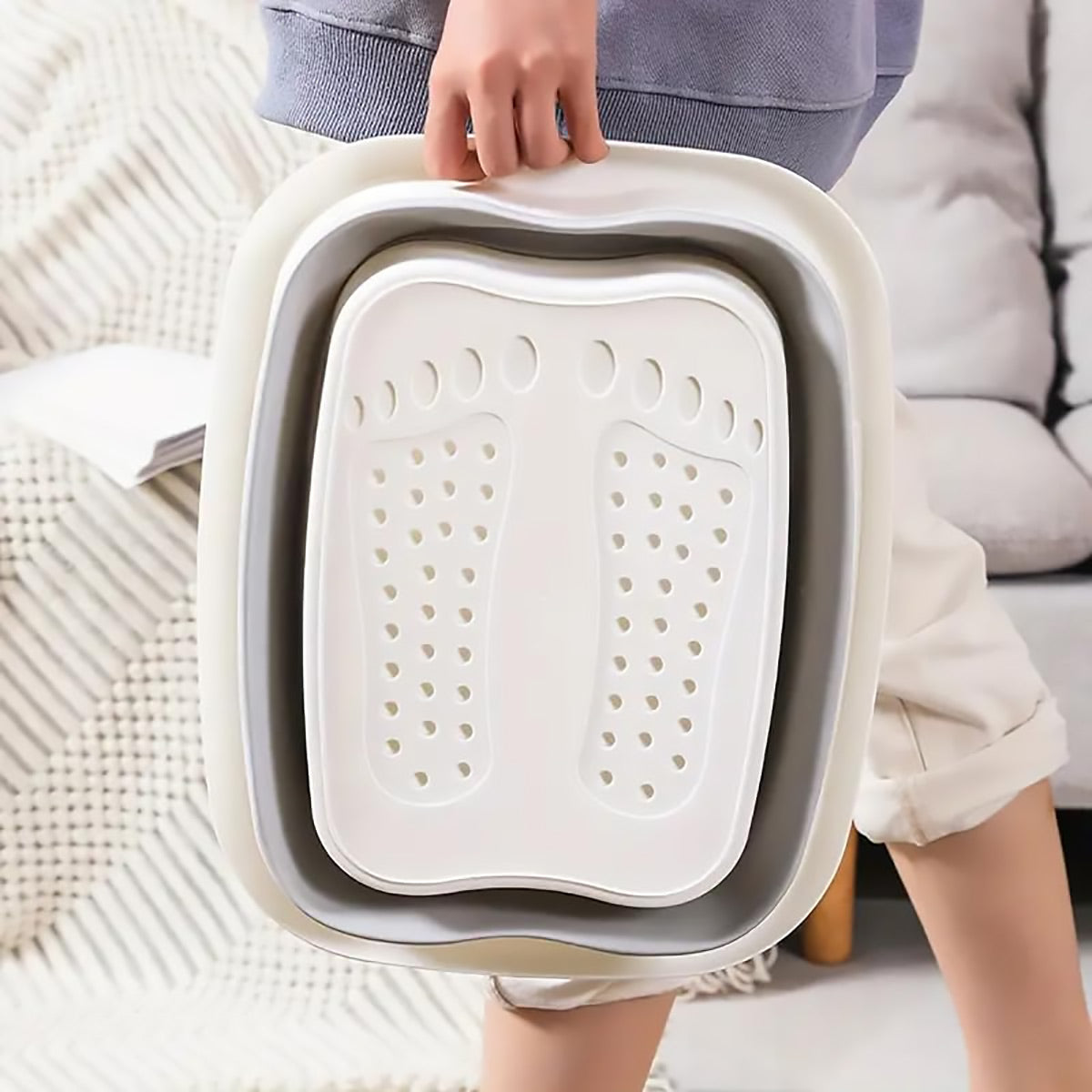 Person holding a gray and white pet litter tray with a textured surface.
