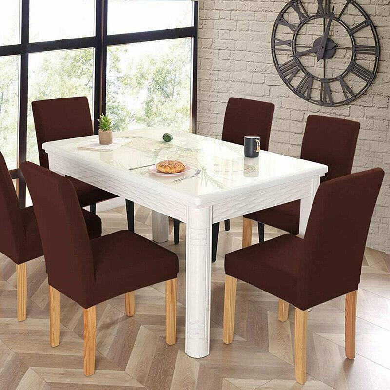 Dining room with a white table and brown chairs against a brick wall.