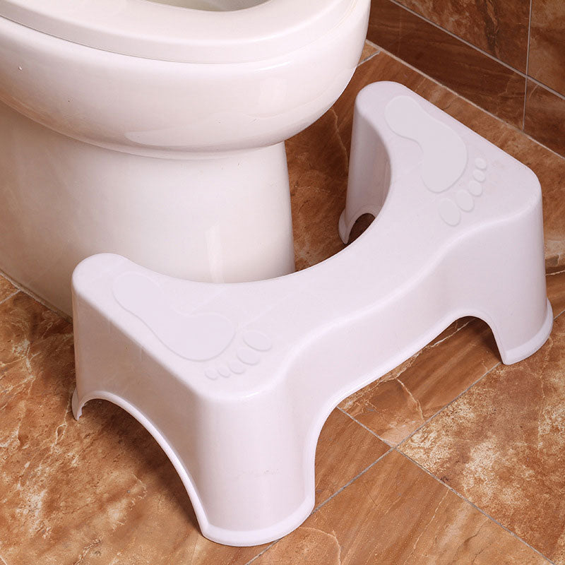 White step stool on a tiled bathroom floor next to a toilet.