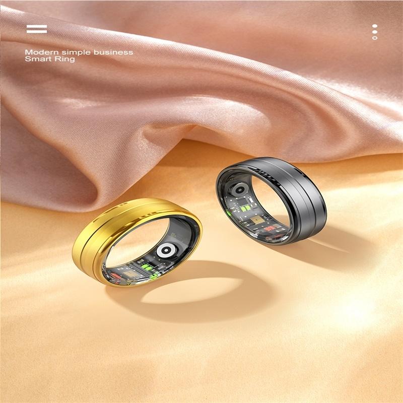 Two smart rings, one gold and one black, on a soft fabric background.